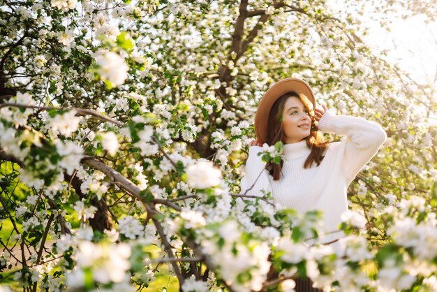 Belle jeune femme près de l'arbre de printemps en fleurs Les jeunes aiment le concept romantique