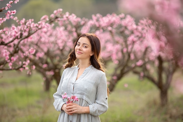 Belle jeune femme près de l'arbre de printemps en fleurs