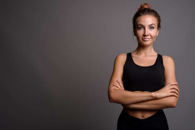 Belle jeune femme prête pour la gym contre le mur gris