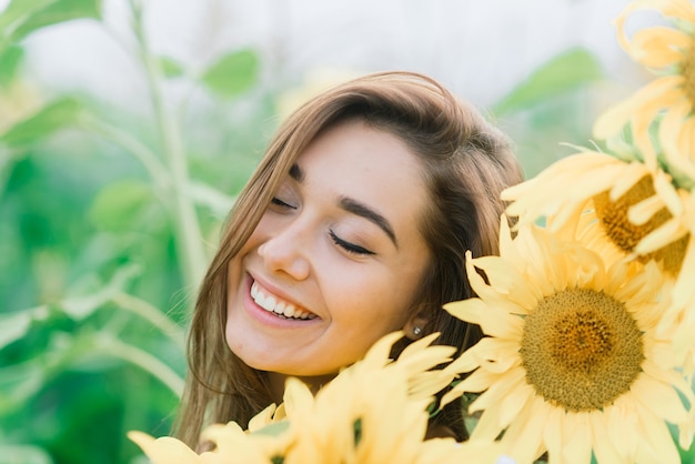 Belle jeune femme profitant de la nature sur le champ de tournesols au coucher du soleil