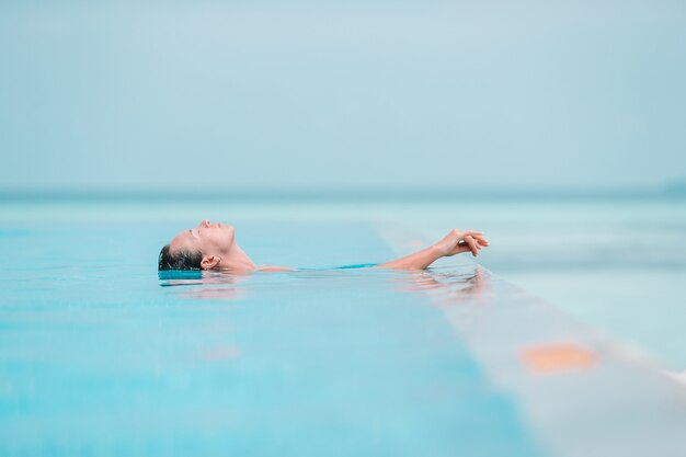 Belle jeune femme profitant des vacances d'été dans la piscine de luxe