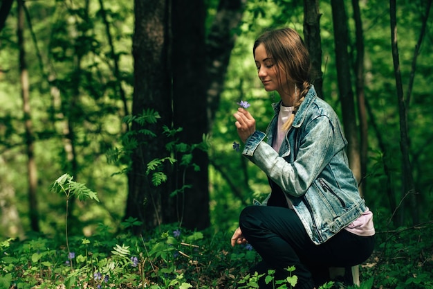 belle jeune femme en promenade dans une forêt verte cueille des fleurs