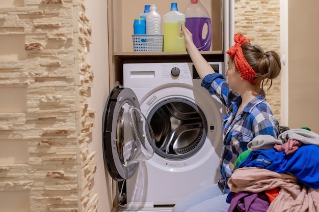 Photo une belle jeune femme qui fait la lessive, les tâches ménagères.