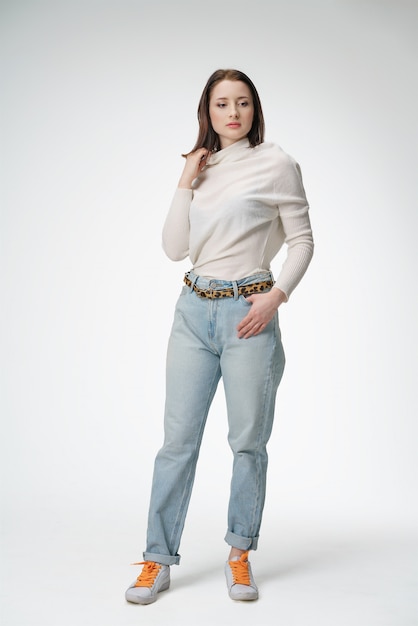 Belle jeune femme qui pose en jeans sur fond blanc