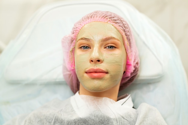 Belle jeune femme à la réception de l'esthéticienne fait un masque anti-âge rajeunissant