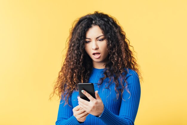 Belle jeune femme regardant smartphone. Bouche grande ouverte choquée expression faciale surprise. Omg coup de nouvelles.