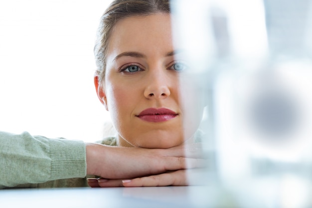 Belle jeune femme regardant un verre avec une pilule effervescente.