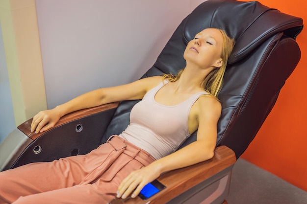 Belle jeune femme relaxante sur le fauteuil de massage à l'aéroport ou dans le centre commercial