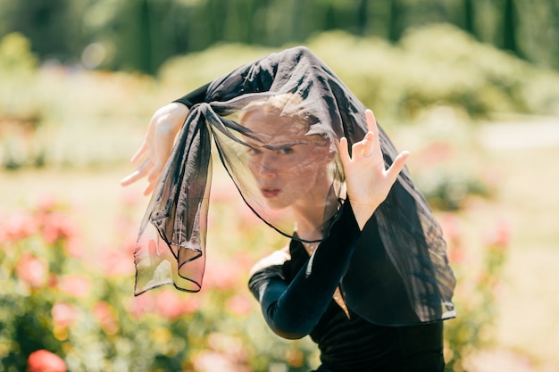 Belle jeune femme en robe à l'ancienne noire posant dans le parc ensoleillé