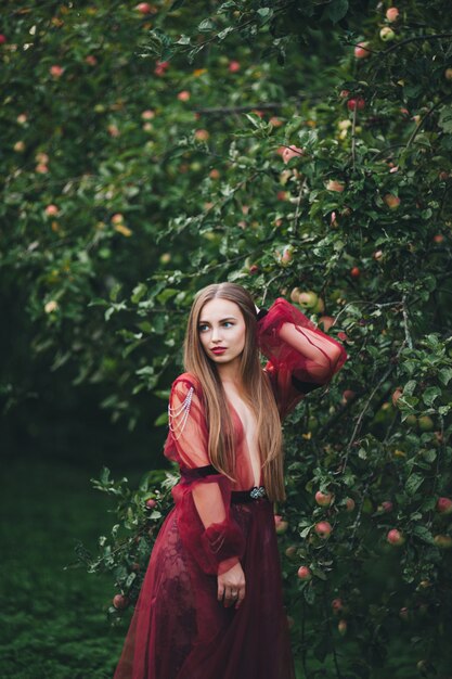 Une belle jeune femme en robe de barde regarde dans les champs et le jardin.