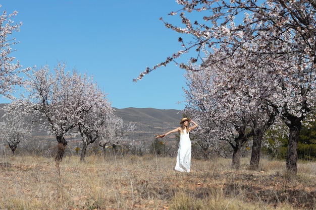 Belle jeune femme en robe blanche et chapeau profitant de la nature