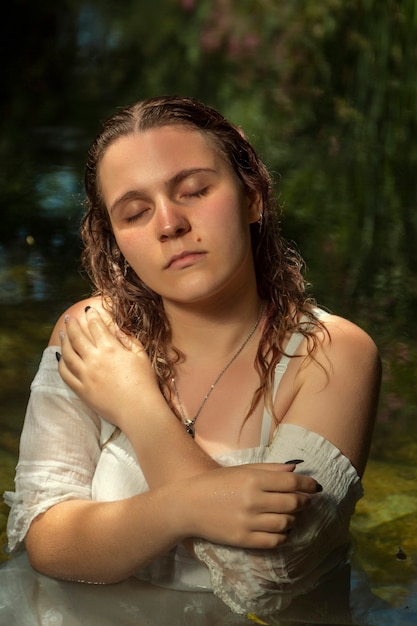 Belle jeune femme avec une robe blanche près du jet d'eau.