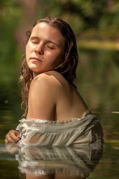 Belle jeune femme avec une robe blanche près du jet d'eau.
