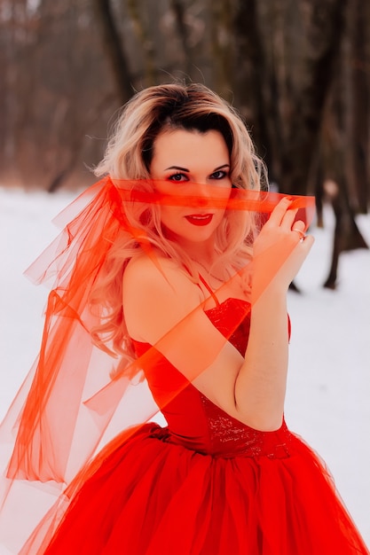 Belle jeune femme en robe longue rouge dans la neige