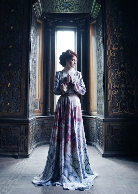 Belle jeune femme en robe rose posant dans un palais de luxe