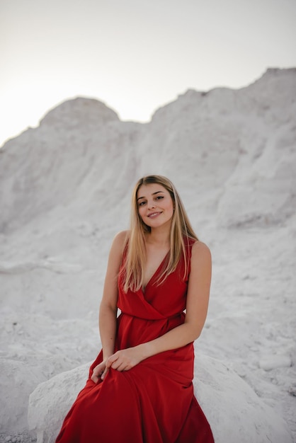 Belle jeune femme en robe rouge rit et fait des gestes