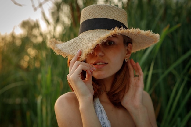 Belle jeune femme en robe de style bohème et chapeau dans la nature