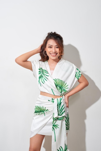 Belle jeune femme en robe verte et blanche imprimé tropical