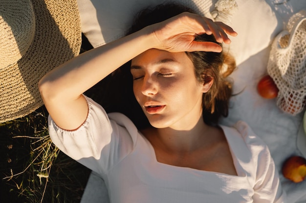 Belle jeune femme romantique allongée sur une couverture sur une prairie d'été Temps pour soi Se détendre sur une prairie d'été Une fille aux beaux cheveux profite du temps estival