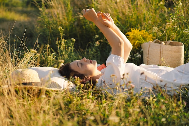 Belle jeune femme romantique allongée sur une couverture sur une prairie d'été Temps pour soi Se détendre sur une prairie d'été Une fille avec de beaux cheveux profite du temps d'été