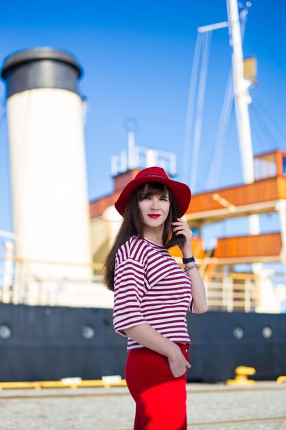 Belle jeune femme en rouge posant sur grand yacht vintage