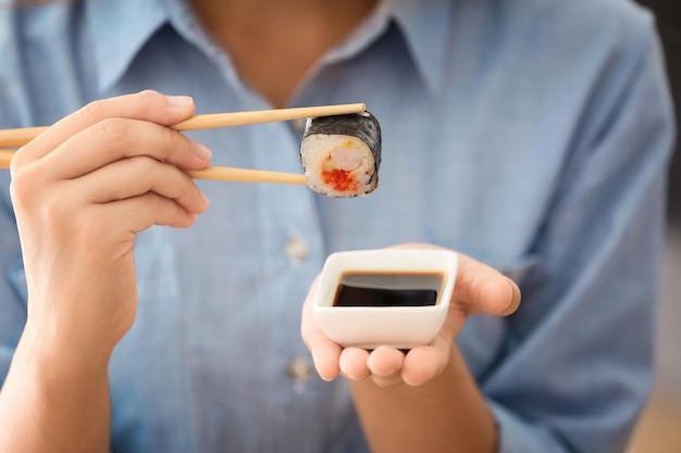 Belle jeune femme avec rouleau de sushi et gros plan de sauce