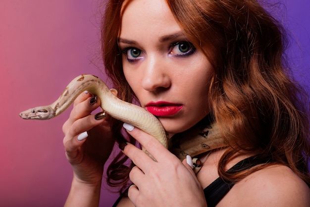 Belle jeune femme rousse avec un serpent avec un maquillage parfait à la mode