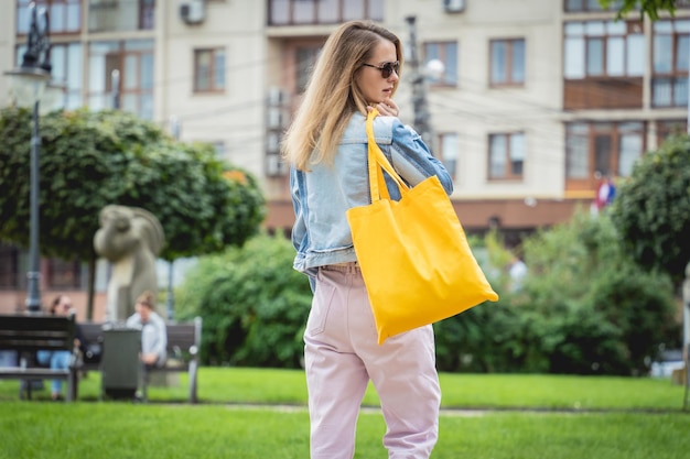 Belle jeune femme avec un sac écologique en lin sur fond de ville