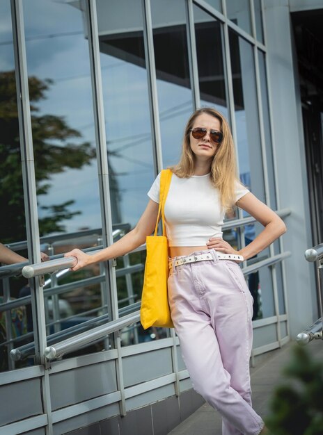 Belle jeune femme avec un sac écologique en lin sur fond de ville