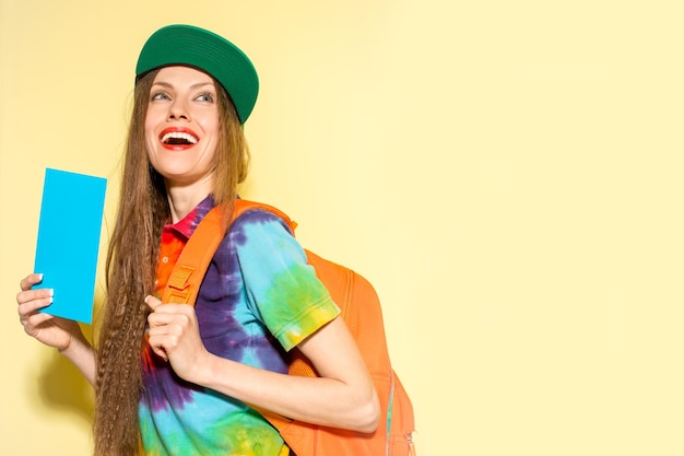 Belle jeune femme avec sac de voyage sur fond jaune