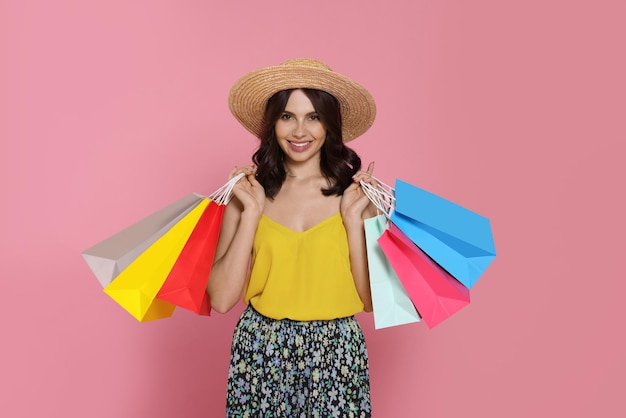 Belle jeune femme avec des sacs en papier sur fond rose