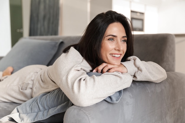 Belle jeune femme se détendre sur un canapé à la maison