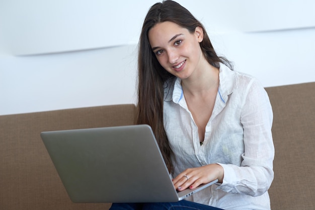 belle jeune femme se détendre et travailler sur un ordinateur portable bureau à domicile moderne tout en écoutant de la musique sur un casque blanc