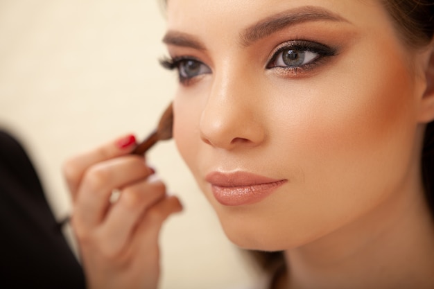 Belle jeune femme se fait un maquillage professionnel