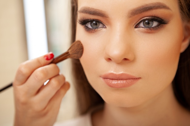 Photo belle jeune femme se fait un maquillage professionnel