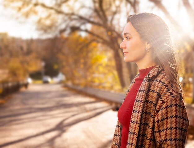 Une belle jeune femme se promène dans le parc un jour ensoleillé d'automne.