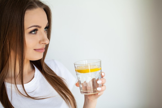 Belle jeune femme se rafraîchissant avec de l'eau citronnée