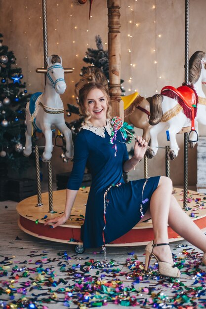 Belle jeune femme se réjouit près d'un manège à chevaux. Noël.