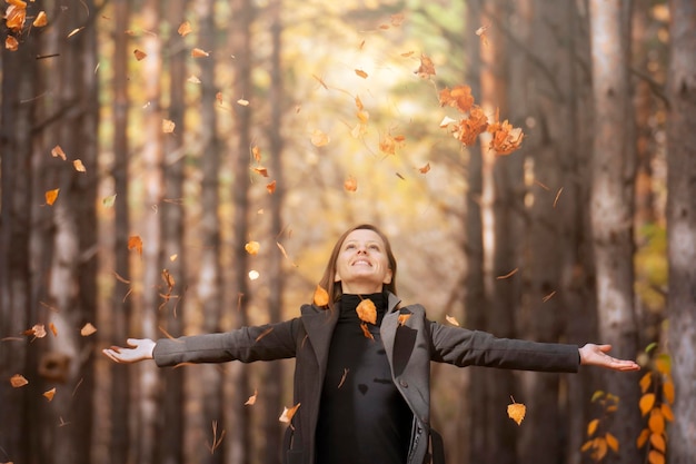 Une belle jeune femme se repose dans le parc pendant la saison d'automne avec les yeux fermés Le souffle de l'automne et le changement de saisons qui tombent des arbres l'air frais et la liberté