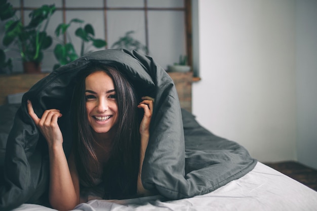 Belle jeune femme se réveillant le matin complètement reposée.