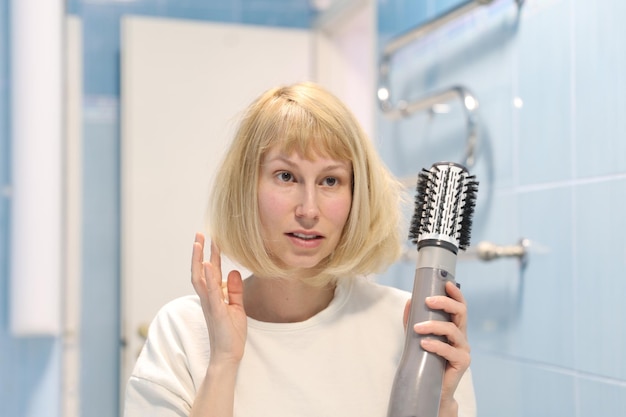 Belle jeune femme sèche et coiffe votre sèche-cheveux