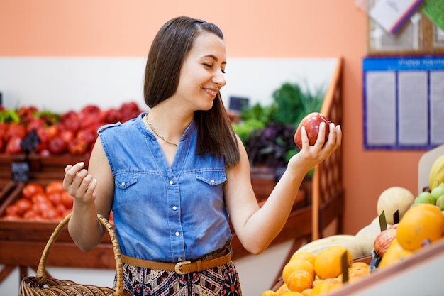 Belle jeune femme sélectionne des pommes dans un magasin de légumes