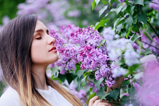 Belle jeune femme sentant un lilas