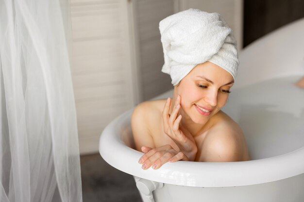 Belle jeune femme avec une serviette sur la tête dans un bain avec du lait