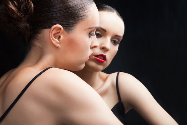 Belle jeune femme sexy près d'un miroir sur fond noir