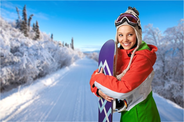 Une belle jeune femme en snowboard souriant sur une montagne enneigée