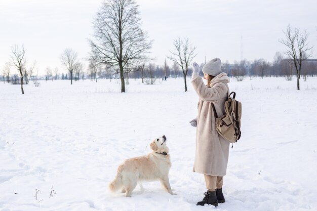 Belle jeune femme et son chien golden retriever s'amusant en hiver