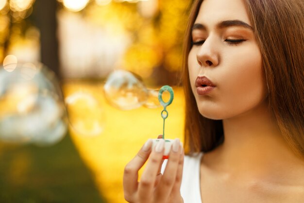 Belle jeune femme soufflant des bulles de savon