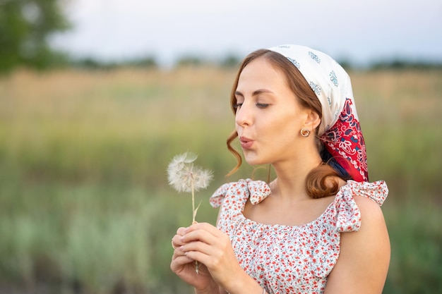 Belle jeune femme souffle un gros pissenlit dans une forêt au coucher du soleil Concept sans allergie