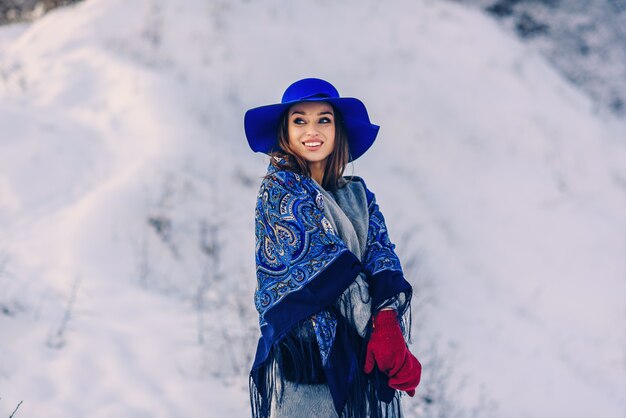 Belle jeune femme souriante au chapeau bleu et écharpe